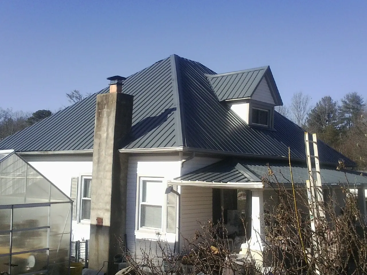 Dark blue standing seam metal roof on a white farmhouse with dormer — Slate & Tile Roof Repair by Roofing Brothers in Stantonsburg