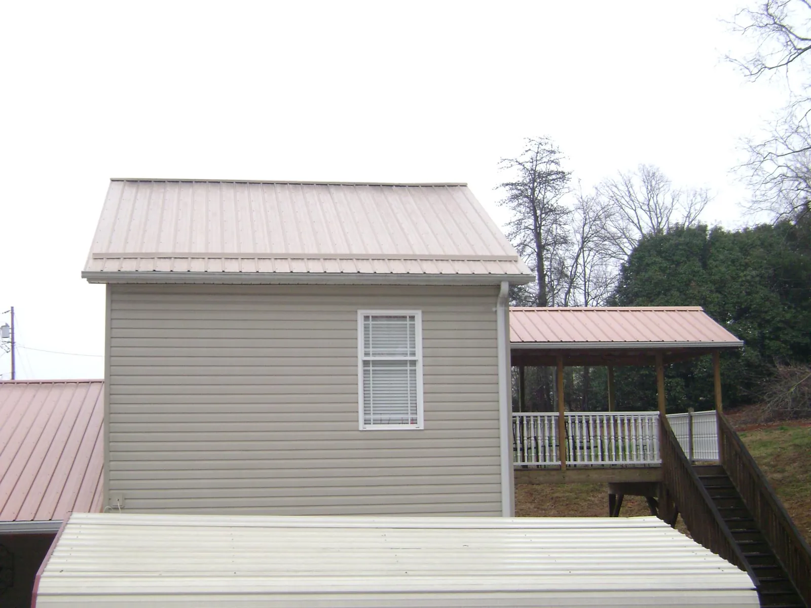 Tan metal roofs on a two story addition and attached porch, from a Roof Replacement job in Stantonsburg
