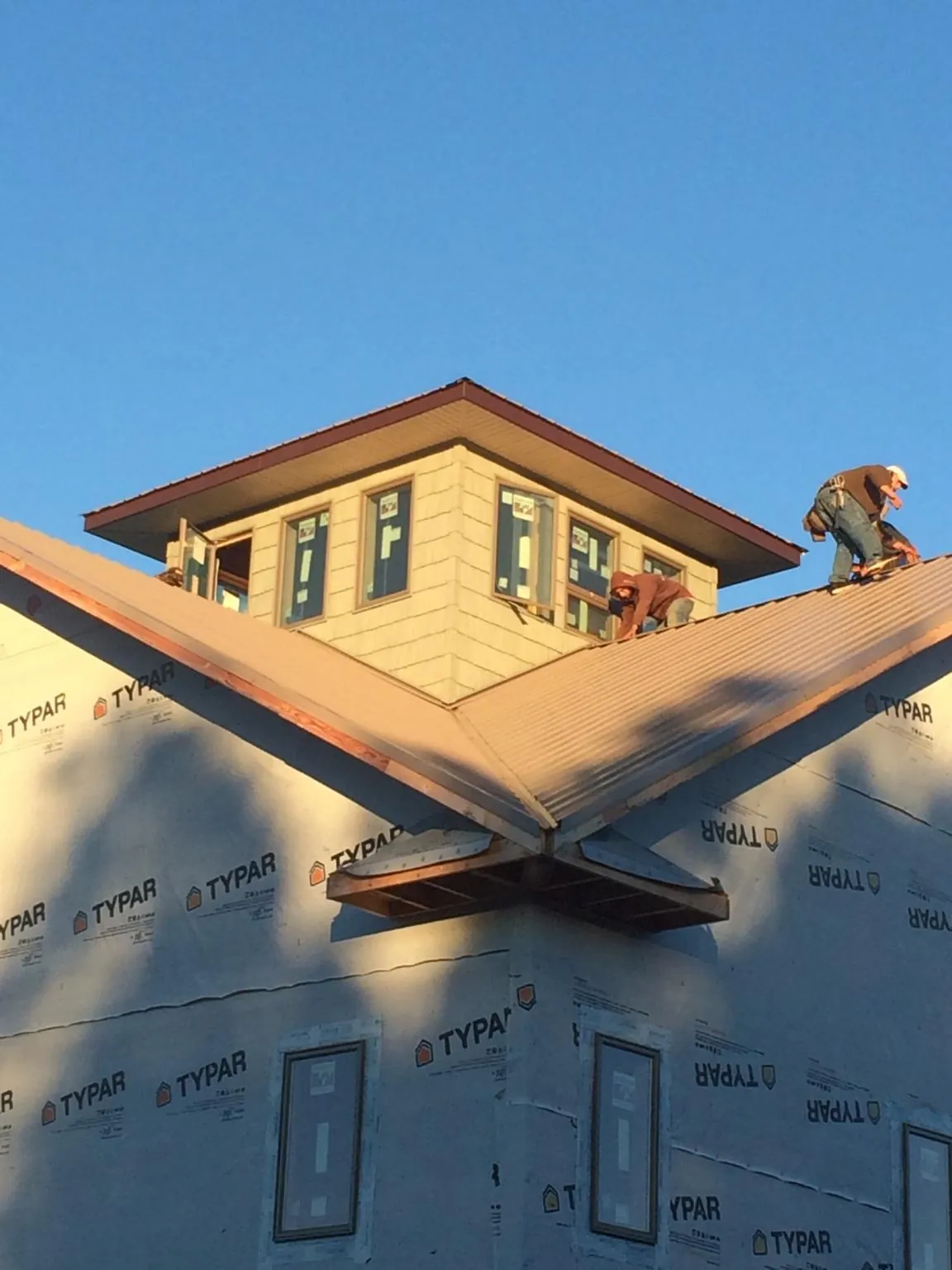 Roofers working around a rooftop cupola on a new metal roof at sunset — Roof Waterproofing in Stantonsburg by Roofing Brothers